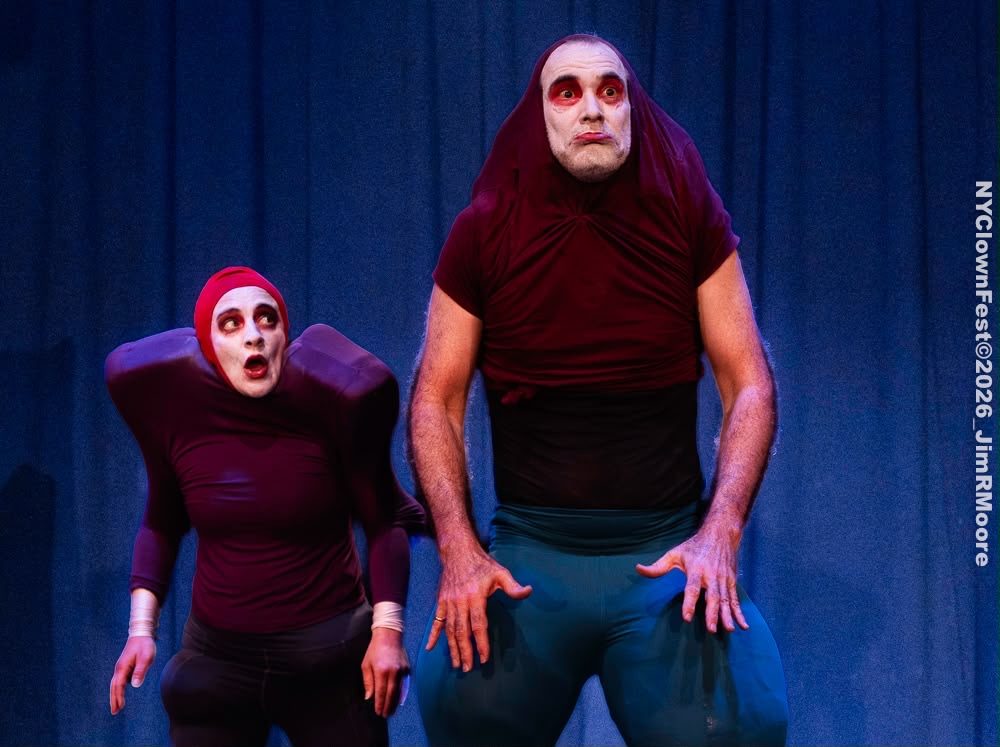 The two bouffons stand side by side in front of a blue curtain, one small and hunched, one tall with enormous padded thighs.