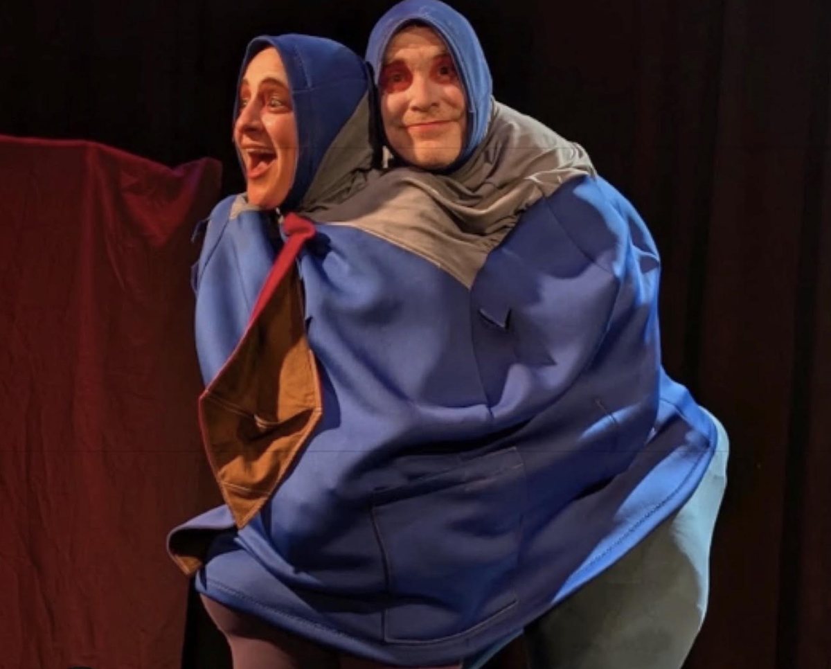 The two bouffons squeezed into one huge padded blue costume, heads poking out of matching blue hoods, one cackling and one grinning.